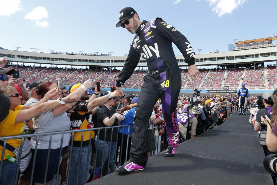 FILE - Jimmie Johnson greets fans during driver introductions prior to a NASCAR Cup Series auto race at Phoenix Raceway, March 8, 2020, in Avondale, Ariz. Seven-time NASCAR champion Jimmie Johnson is returning to NASCAR two years after his retirement from the stock car series. Johnson bought a stake in GMS Petty Racing, a Cup team fronted by seven-time champion Richard Petty. (AP Photo/Ralph Freso, File)