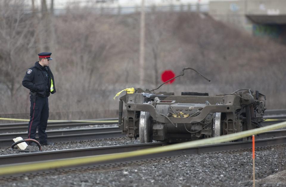 A police officer stands beside a piece of train wheels that fell off a Via Rail passenger train in Burlington, Ontario on Sunday, Feb. 26, 2012. Burlington Mayor Rick Goldring says three people are dead after the Toronto-bound train derailed in his town. (AP Photo/The Canadian Press, Pawel Dwulit)