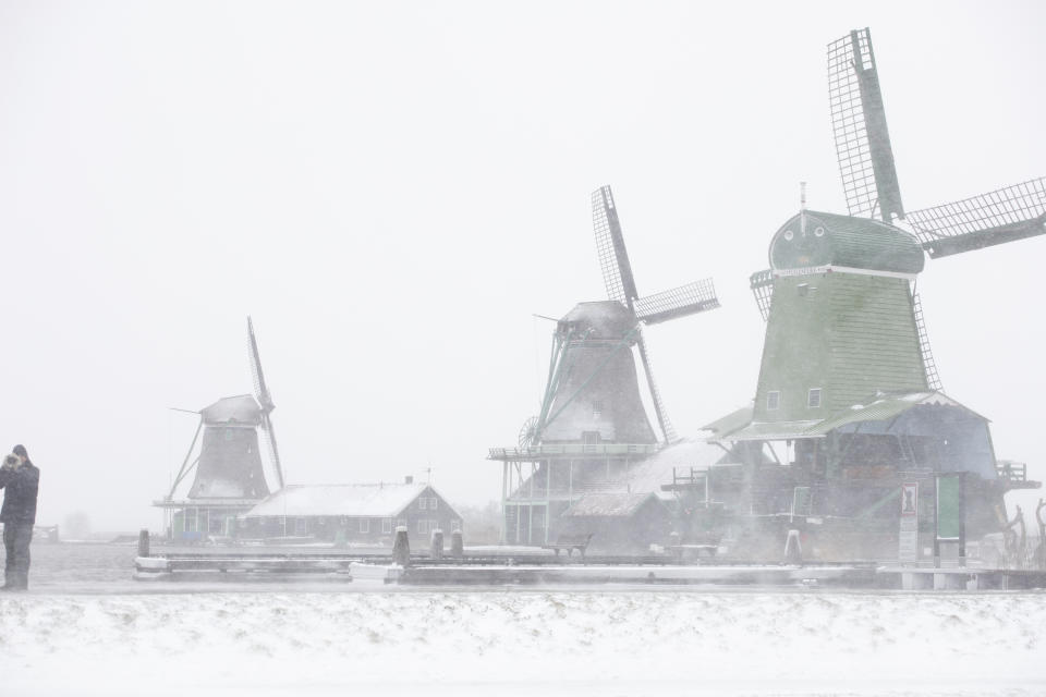 A man takes pictures at the Zaans Museum in Zaandam, as snow and strong winds pounded The Netherlands, Sunday, Feb. 7, 2021. (AP Photo/Peter Dejong)