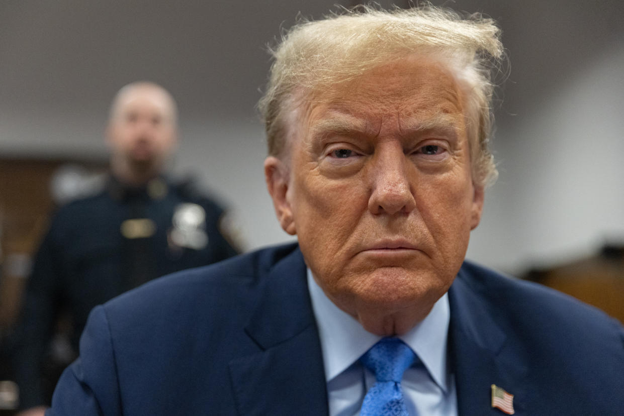 Donald Trump looks at the camera as he sits in Manhattan criminal court.