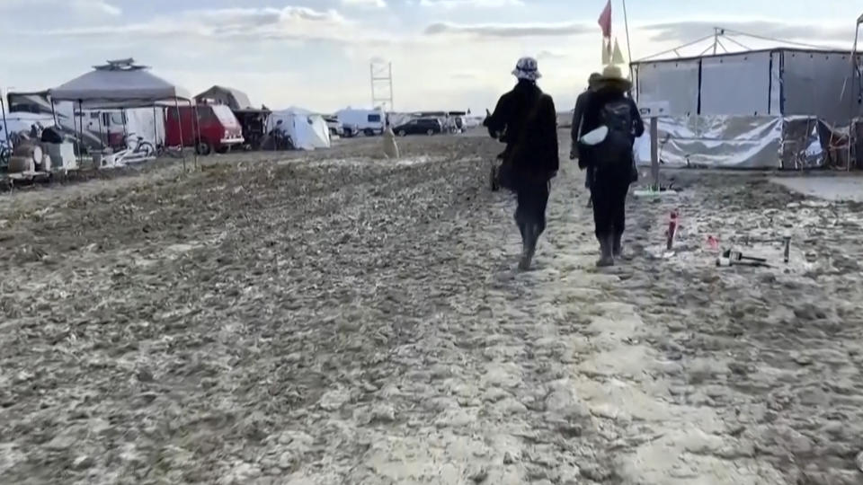 CORRECTS THAT THE SOURCE IS STRINGR, NOT REBECCA BARGER - In this image from video provided by Stringr, people walk along a muddy path at the Burning Man festival site in Black Rock, Nev., on Monday, Sept. 4, 2023. An unusual late-summer storm stranded thousands at the week-long event. (Stringr via AP)