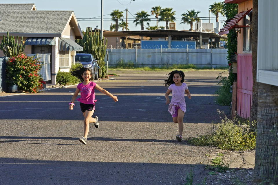 Children play outside their homes at the Periwinkle Mobile Home Park, Thursday, April 11, 2023, in Phoenix. Residents of the park are facing an eviction deadline of May 28 due to a private university's plan to redevelop the land for student housing. (AP Photo/Matt York)