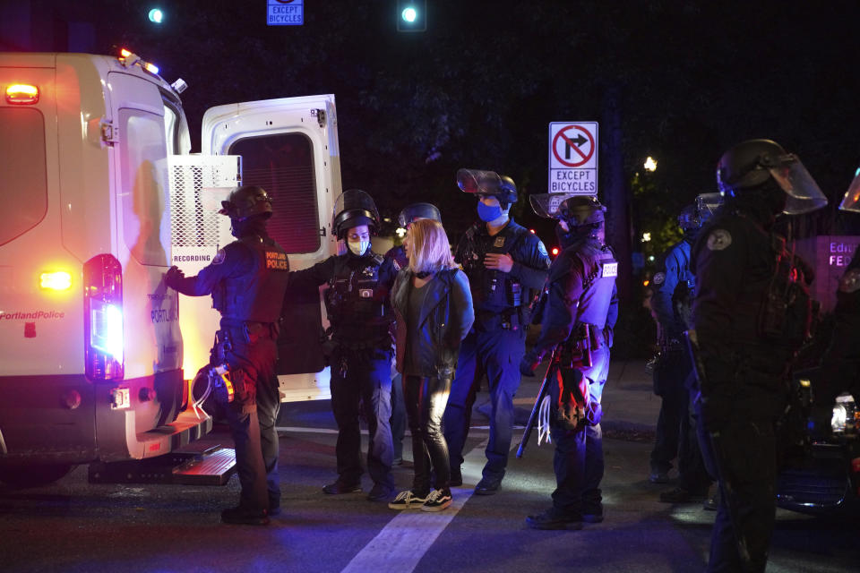 A female protester is loaded into a van after being arrested while rallying at the Mark O. Hatfield United States Courthouse on Saturday, Sept. 26, 2020, in Portland, Ore. The rally came as Portland has seen nearly nightly protests since the police killing of George Floyd in late May. (AP Photo/Allison Dinner)