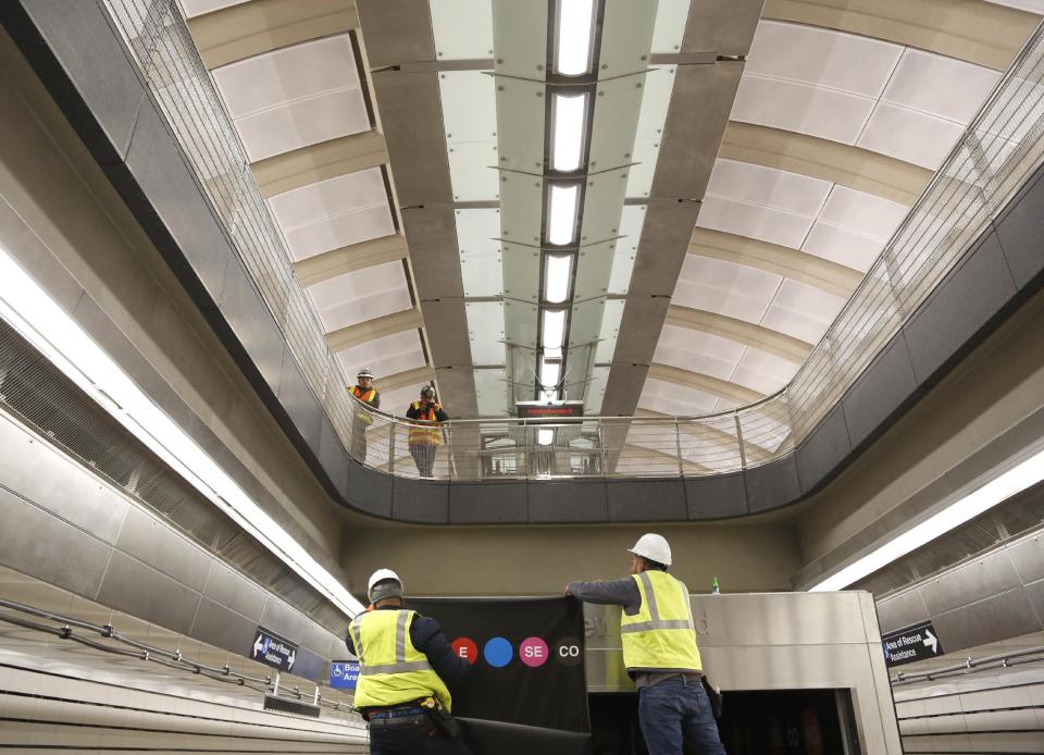 FILE- In this Dec. 22, 2016 file photo, workers put the finishing touches on the new 86th Street subway station on the Second Avenue Subway in New York. Straphangers' long wait to take a subway under Manhattan's far Upper East Side ends at noon on Sunday, Jan. 1, 2017, with the inaugural ride of the Second Avenue line. (AP Photo/Seth Wenig)