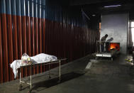 A worker prepares to cremate the body of a COVID-19 victim in New Delhi, India, Monday, April 19, 2021. India's health system is collapsing under the worst surge in coronavirus infections that it has seen so far. Medical oxygen is scarce. Intensive care units are full. Nearly all ventilators are in use, and the dead are piling up at crematoriums and graveyards. Such tragedies are familiar from surges in other parts of the world — but were largely unknown in India. (AP Photo/Manish Swarup)