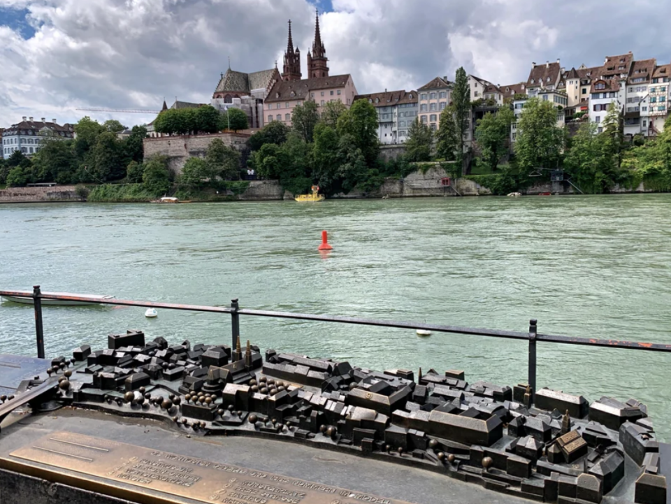 View of a river with a cityscape in the background and a miniature scale model of buildings in the foreground