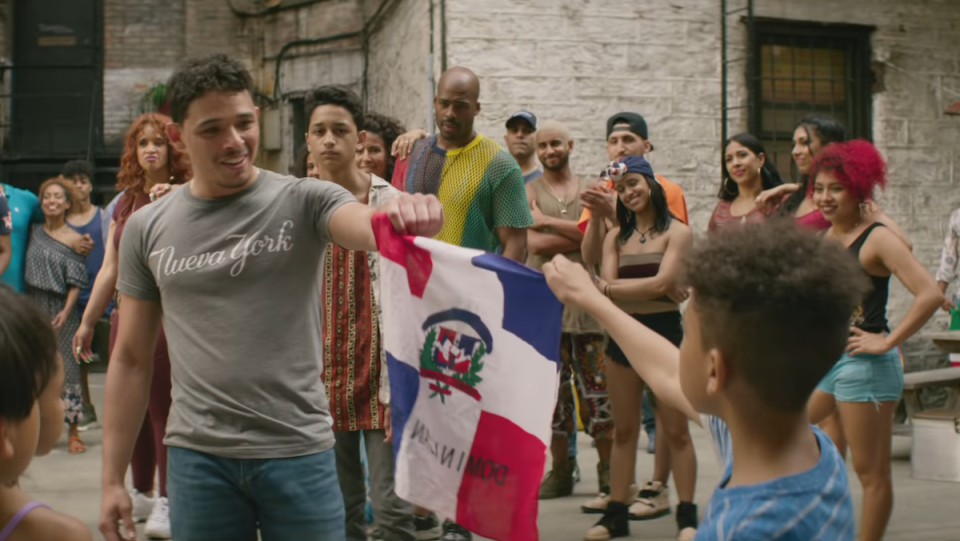 Usnavi and a young boy hold the Dominican flag together.