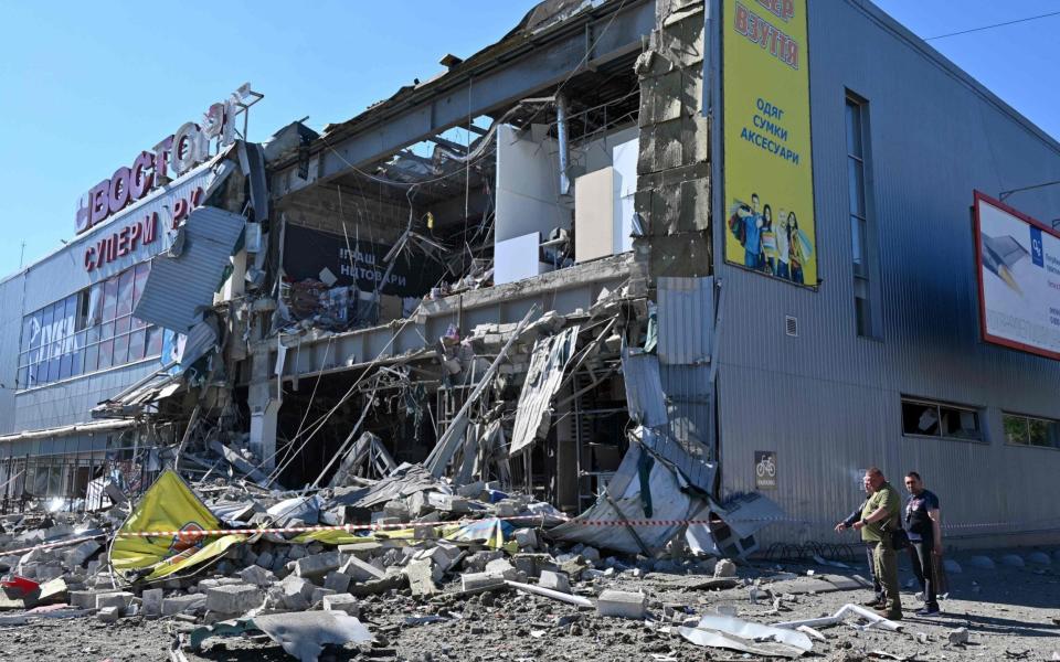 People look at a supermarket partially destroyed by a missile attack on the southeastern outskirts of the Ukrainian city of Kharkiv on June 8, 2022. - Sergey Bobok/AFP