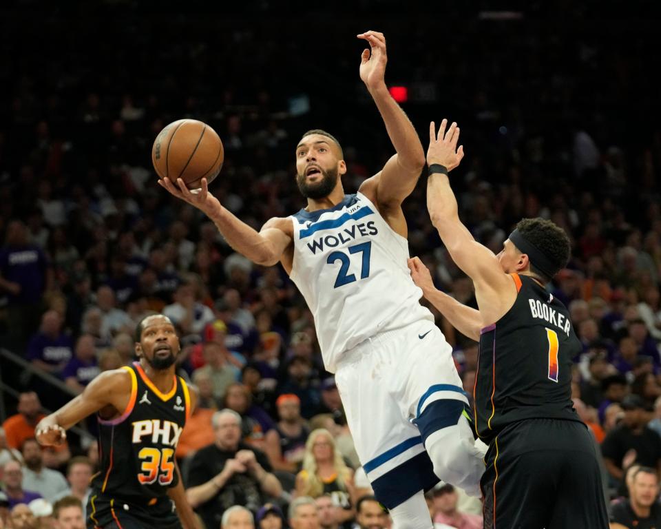 Minnesota Timberwolves center Rudy Gobert (27) lays a shot up against Phoenix Suns guard Devin Booker (1) during game 4 of the Western Conference first round series at Footprint Center on Sunday, April 28, 2024.