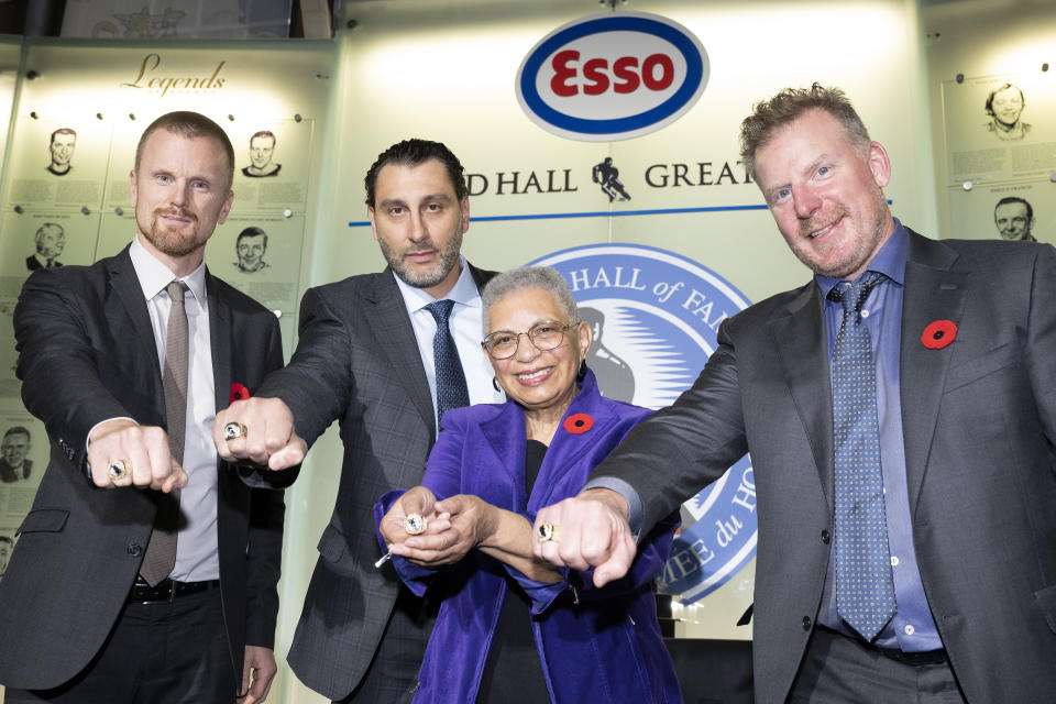 Daniel Sedin, left to right, Roberto Luongo, Herb Carnegie's daughter Bernice Carnegie, and Daniel Alfredsson pose with their rings during a ceremony to celebrate the latest inductees into the 'Hockey Hall of Fame' at an event in Toronto, Friday, Nov. 11, 2022. (Chris Young/The Canadian Press via AP)