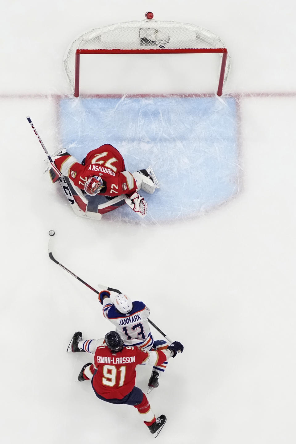 Edmonton Oilers center Mattias Janmark (13) shoots on Florida Panthers goaltender Sergei Bobrovsky (72) as Panthers' Oliver Ekman-Larsson (91) defends during the first period of Game 1 of the Stanley Cup Finals, Saturday, June 8, 2024, in Sunrise, Fla. (AP Photo/Wilfredo Lee)