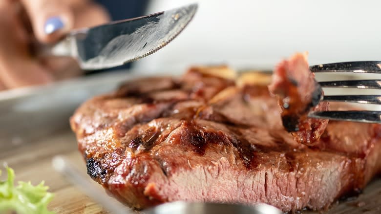 person cutting into steak