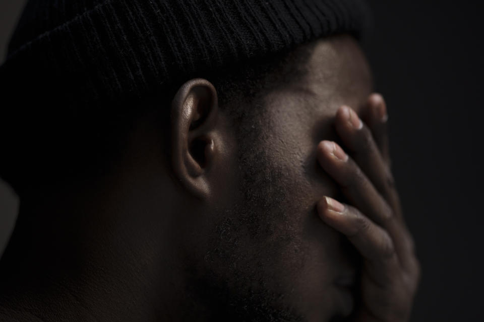 Moussa Sako, an asylum-seeker from Mali who survived 22 days aboard a Mauritanian boat drifting in the Atlantic Ocean, covers his face during an interview in Guadalajara, Spain, Sunday, Nov. 14, 2021. Sako was rescued by the Spanish Air Force on April 26, 2021. His boat was spotted by chance more than 310 miles (500 km) from the Spanish island of El Hierro — “in the middle of nowhere,” as one of the rescuers described it. They had set off 22 days earlier from Nouakchott, the capital of Mauritania. Only three of 63 people who boarded survived. (AP Photo/Felipe Dana)