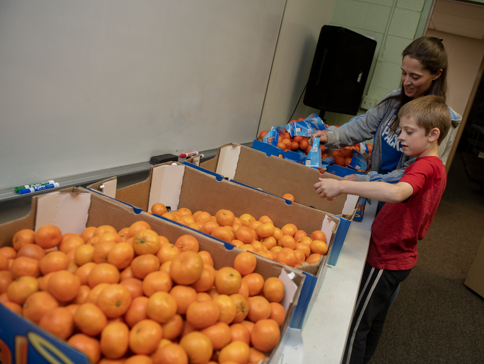 Laura Wunderle, a Raven Packs founder and its treasurer, sorts out bad mandarins with her son 8-year-old son, Bennett.