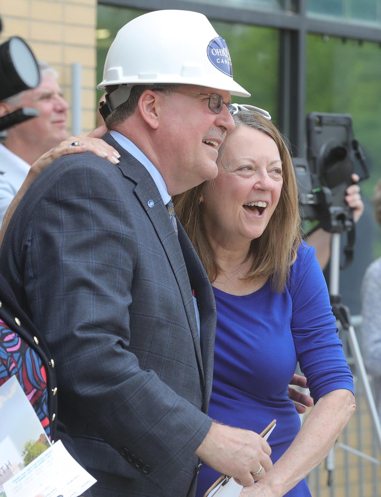 Ohio & Erie Canalway Coalition CEO and President Dan Rice gets a hug from Becky Considine as the final beam for the Maynard Performance Pavilion is lifted by crane during a "topping off" ceremony at Lock 3 Park on Tuesday, May 7, 2024, in Akron.