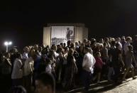 An image of Cuba's late President Fidel Castro hangs on a building as people wait in the early evening to to pay tribute to Castro at the Jose Marti Memorial in Revolution Square in Havana, Cuba, November 28, 2016. REUTERS/Carlos Garcia Rawlins