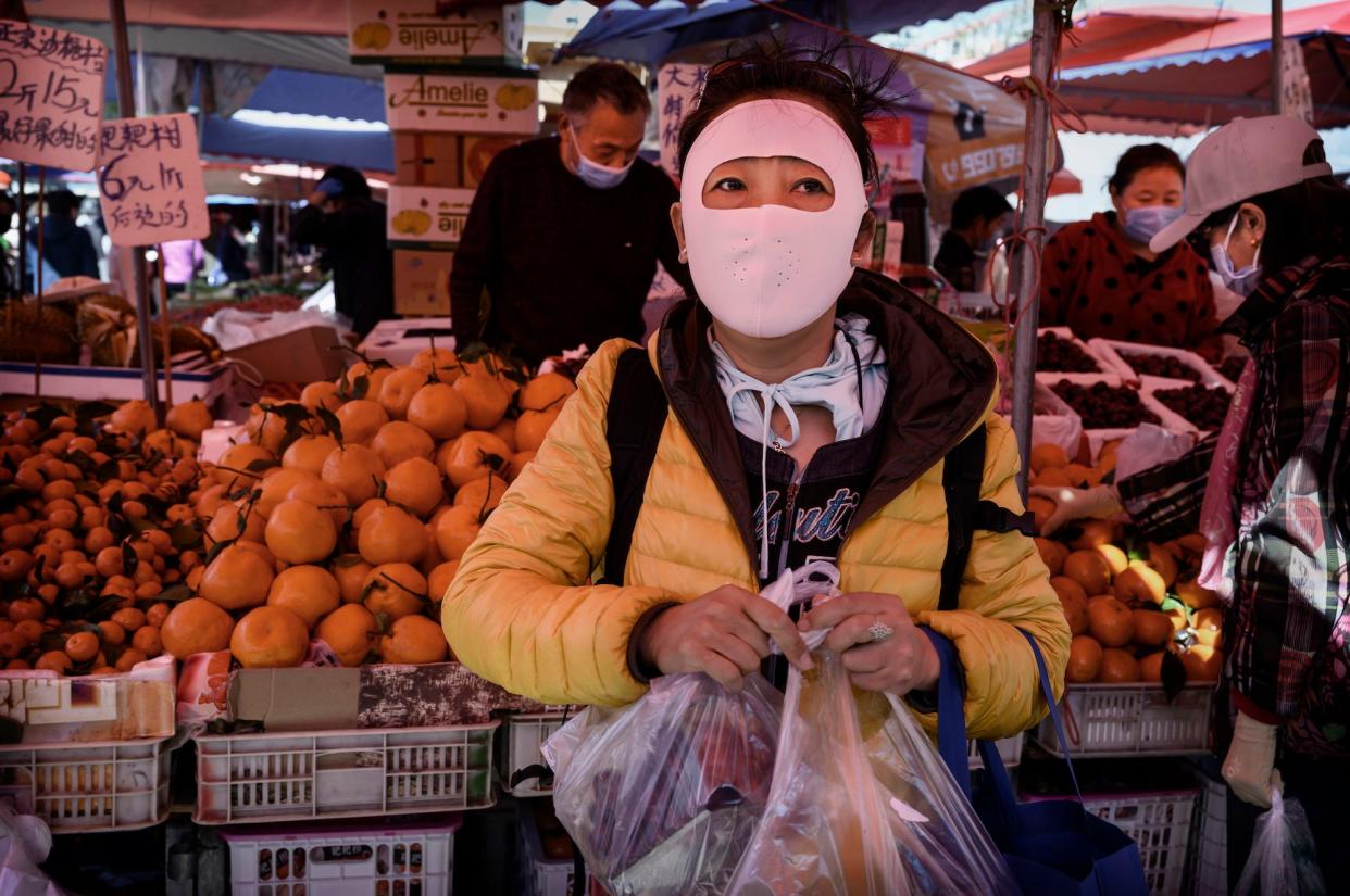 APRIL 03: A Chinese woman wears a full face protective mask as she shops at an outdoor food market on April 3, 2020 in Beijing, China