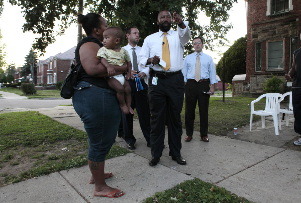 In this Aug. 19, 2009 photo, emergency financial manager Robert Bobb points while talking with Markita Wells, left, holding her son Keenan, while walking neighborhoods trying to convince parents to enroll their children in Detroit Public School in Detroit. (AP Photo/Paul Sancya)