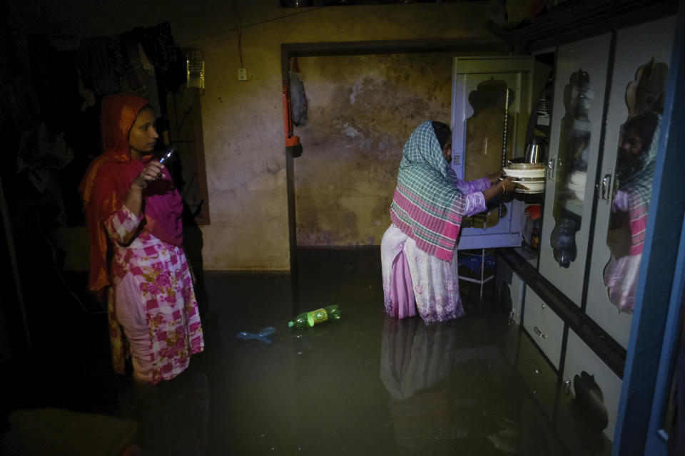 Two women stand inside a flooded home in Sylhet, Bangladesh, Monday, June 20, 2022. Floods in Bangladesh continued to wreak havoc Monday with authorities struggling to ferry drinking water and dry food to flood shelters across the country’s vast northern and northeastern regions. (AP Photo/Mahmud Hossain Opu)