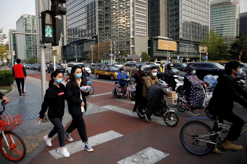 FILE PHOTO: People wearing face masks walk across a street at Beijing's Financial Street during evening rush hour, as the country is hit by an outbreak of the novel coronavirus disease (COVID-19)