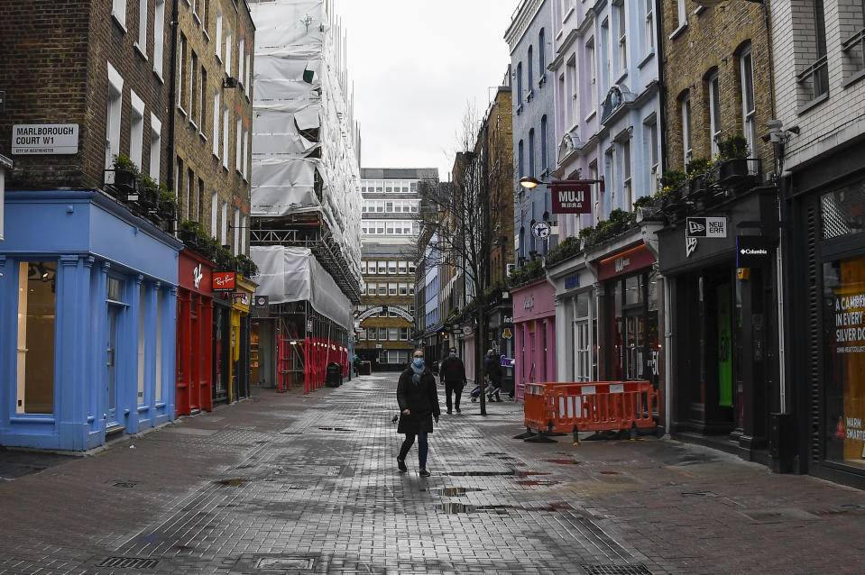 A woman wears a face mask as she walks in a deserted Carnaby Street, in London, Wednesday, Feb. 3, 2021. Britain's Health Secretary Matt Hancock said Wednesday a new study suggesting that a single dose of the AstraZeneca vaccine may reduce transmission of COVID-19 categorically supports the government's strategy of taking more time between injections. (AP Photo/Alberto Pezzali)