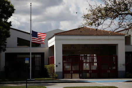 A flag flies at half mast next to the entrance of the Marjory Stoneman Douglas High School, after the police security perimeter was removed, following a mass shooting in Parkland, Florida, U.S., February 18, 2018. REUTERS/Carlos Garcia Rawlins