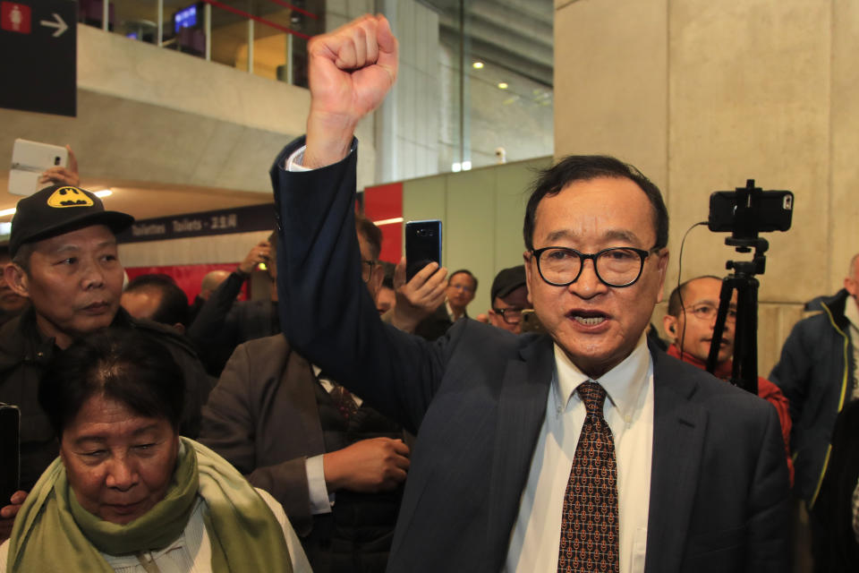 Cambodia's most prominent opposition politician Sam Rainsy clenches his fist as he is attempting to return to Cambodia Thursday, Nov. 7, 2019 at Charles de Gaulle airport, north of Paris. Sam Rainsy is attempting to return to Cambodia from his self-imposed exile to force out the long-serving leadership but may not be let on Thursday's Paris-Bangkok flight. (AP Photo/Michel Euler)