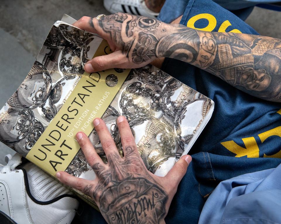 Peter Merts photos show California Prison Arts Programs A student with an art textbook, at Calipatria State Prison - 2018