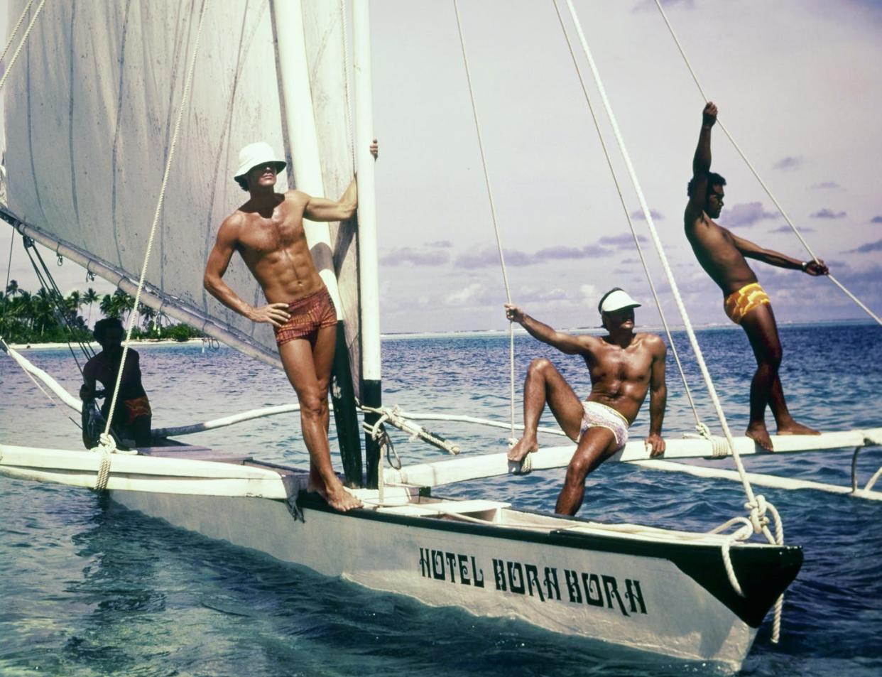 <span class="caption">The ideal male body didn't always include chiseled abs.</span> <span class="attribution"><a class="link " href="https://www.gettyimages.com/detail/news-photo/summer-1975-three-models-pose-on-a-hotel-bora-bora-sailing-news-photo/1171950396?adppopup=true" rel="nofollow noopener" target="_blank" data-ylk="slk:Chris von Wangenheim/Conde Nast via Getty Images;elm:context_link;itc:0;sec:content-canvas">Chris von Wangenheim/Conde Nast via Getty Images</a></span>