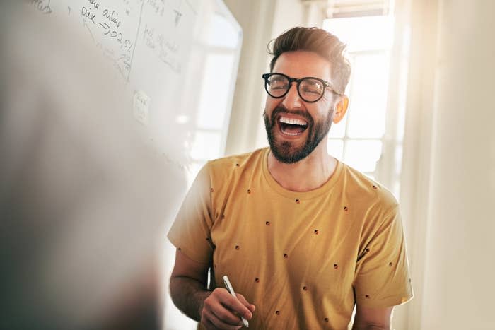 Cropped shot of a team of designers brainstorming together in an office, man laughs