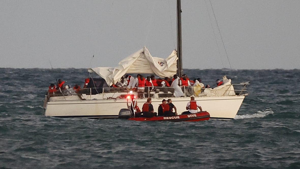 U.S. Coast Guard members pull up alongside a sailboat carrying a large group of migrants off Virginia Key near Key Biscayne, Fla. on Thursday, Jan. 12, 2023. (Al Diaz/Miami Herald via AP)