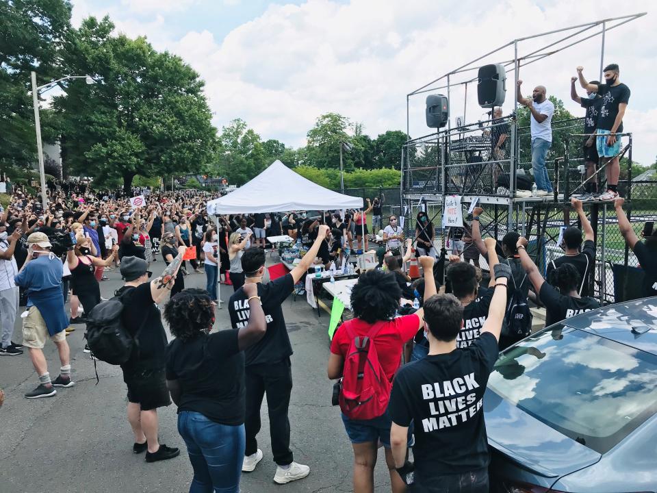 Zellie Imani, an organizer with Paterson's Black Lives Matter group, encourages protesters to raise their fist as he speaks in front of Montclair Kimberly Academy's high school.