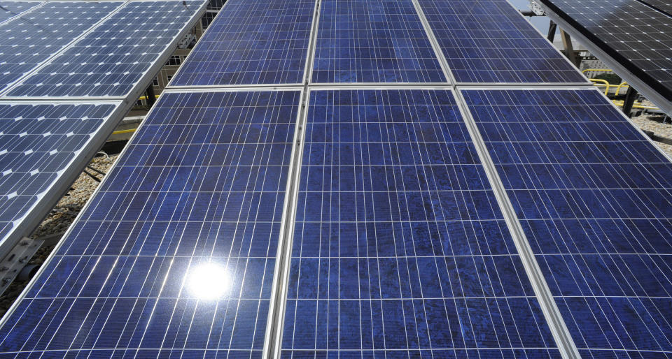 FILE - In this Thursday, Aug. 9, 2012 file photo, sunlight reflects off solar panels on the roof of the older part of the Alabama Power building in Birmingham, Ala. The fees imposed by the Alabama Power company on customers who generate their own electricity with rooftop or on-site solar panels are now the subject of a federal lawsuit against the state's regulators. Environmental groups argue that punishing fees are purposely discouraging the adoption of solar power in the sun-rich state. (Bernard Troncale/The Birmingham News via AP)