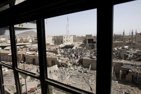 People and vendors gather upon the rubble of shops destroyed by a Saudi-led air strike that hit a marketplace in Yemen's capital Sanaa July 20, 2015. REUTERS/Khaled Abdullah