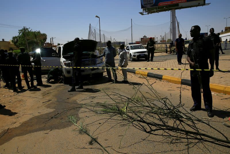 Security personnel stand near a car damaged after an explosion targeting the motorcade of Sudan's Prime Minister Abdalla Hamdok near the Kober Bridge in Khartoum