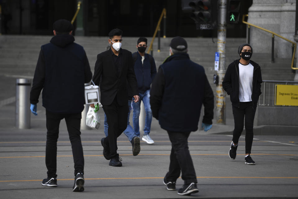 People wearing face masks to help protect against the spread of the new coronavirus walk outside Flinders Street Station in Melbourne, Australia, Thursday, July 23, 2020. There were few bare faces among rush-hour commuters in Australia’s second-largest city on Thursday morning as Melbourne residents were largely complying with a new law making face coverings compulsory. (James Ross/AAP Image via AP)