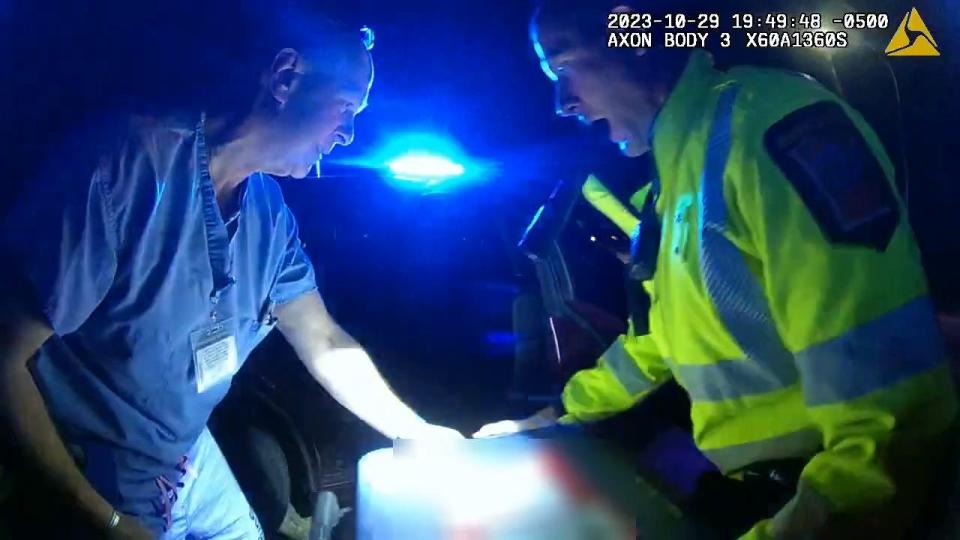 A medical staff member and a state trooper lifting a live human heart into a patrol car in Oct. 2023 so they could take it to Rochester, Minn. for heart transplant surgery.