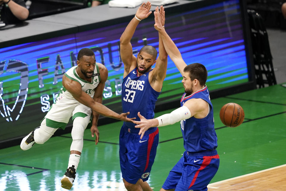Boston Celtics guard Kemba Walker, left, passes the ball in between LA Clippers forward Nicolas Batum (33) and center Ivica Zubac, right, in the first quarter of an NBA basketball game, Tuesday, March 2, 2021, in Boston. (AP Photo/Elise Amendola)
