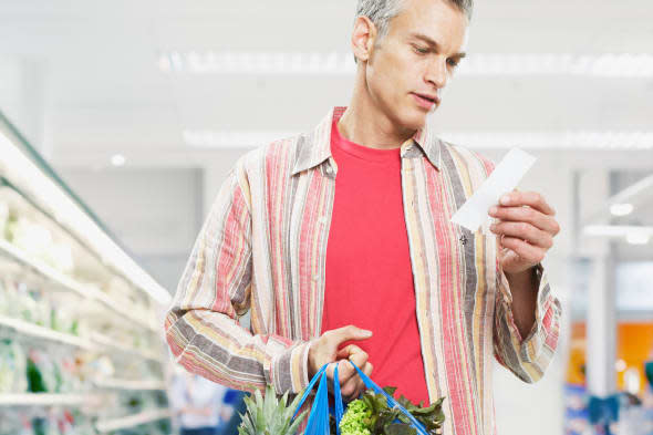 AM38GT Man looking at bill in grocery store. Image shot 2007. Exact date unknown.