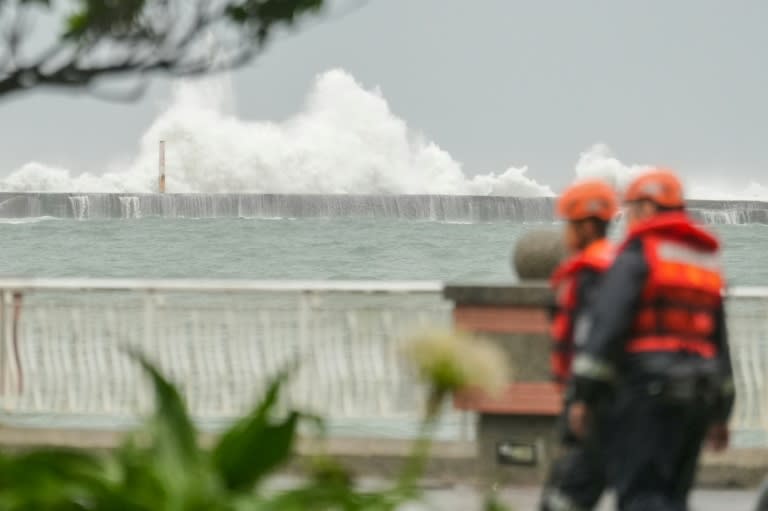 Miembros de la guardia costera de Taiwán caminan frente a los grandes oleajes de la playa Sizihwan, el 2 de octubre de 2024 (WALID BERRAZEG)