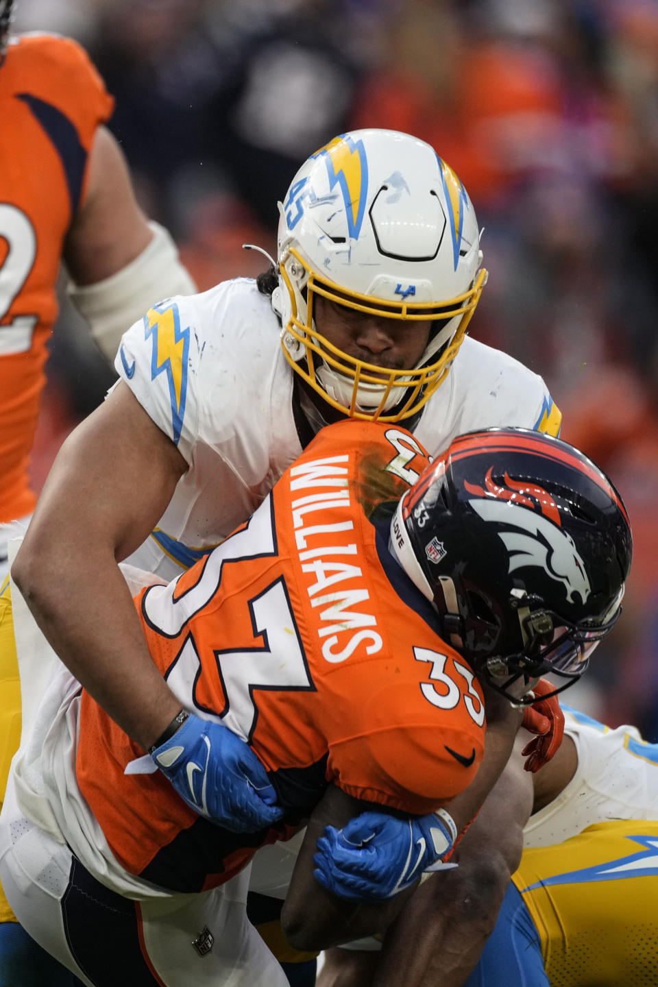 Los Angeles Chargers linebacker Tuli Tuipulotu (45) tackles Denver Broncos running back Javonte Williams (33) during the second half of an NFL football game, Sunday, Dec. 31, 2023, in Denver. (AP Photo/David Zalubowski)