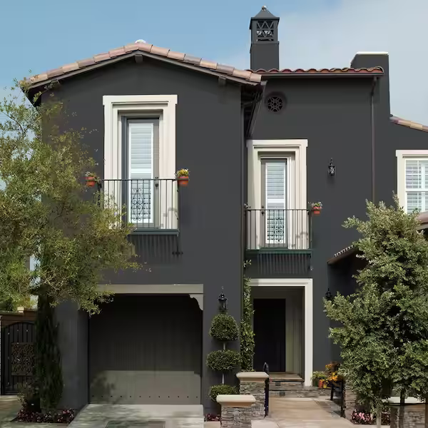 A two story masonry house is painted in a dark grey color.