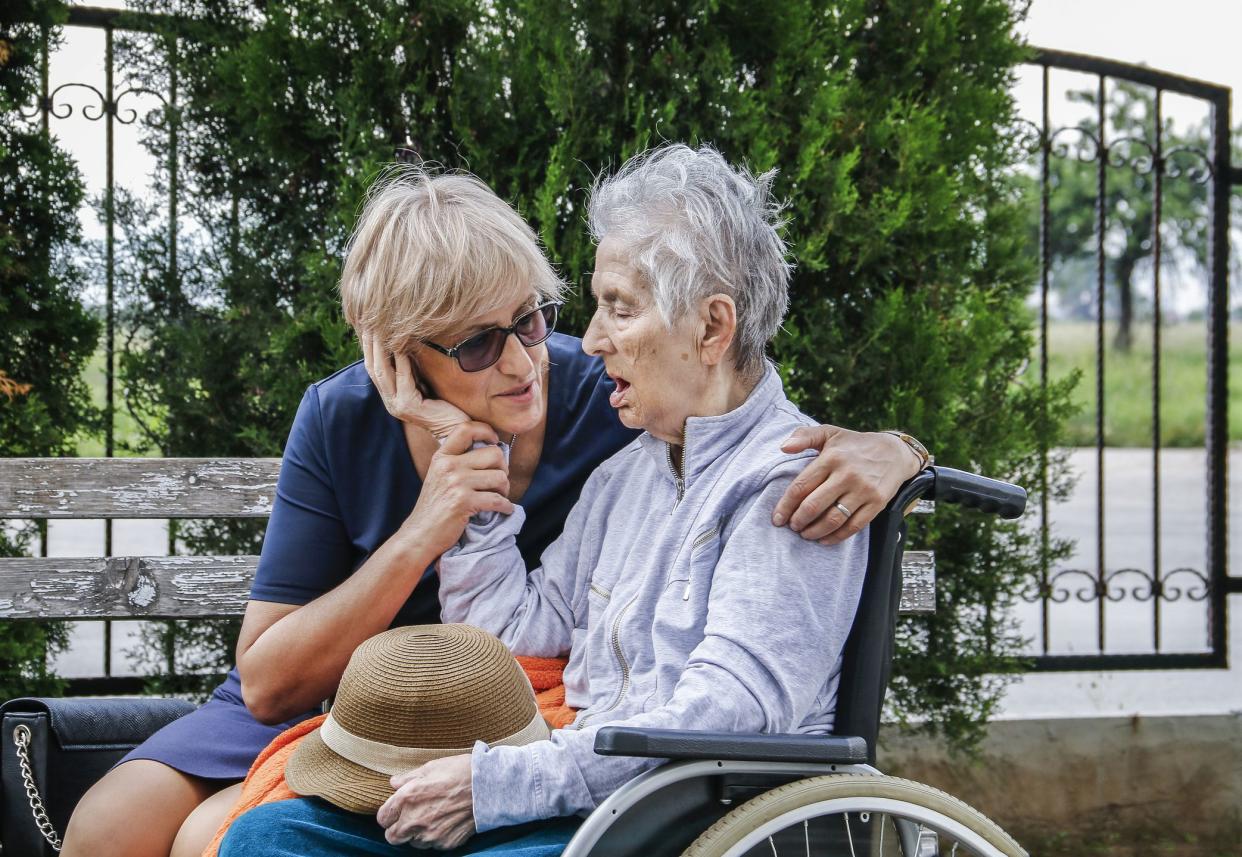 senior woman talking to her mother in wheelchair