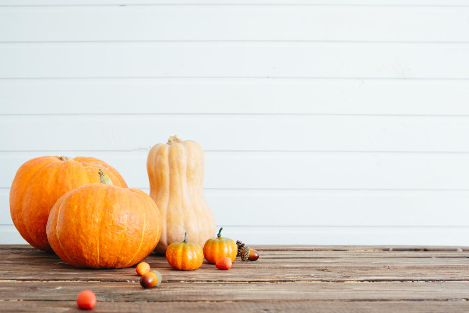 Pumpkins on a wooden table against white wooden wall Organic food and healthy food concept Thanksgiving and Halloween concept.