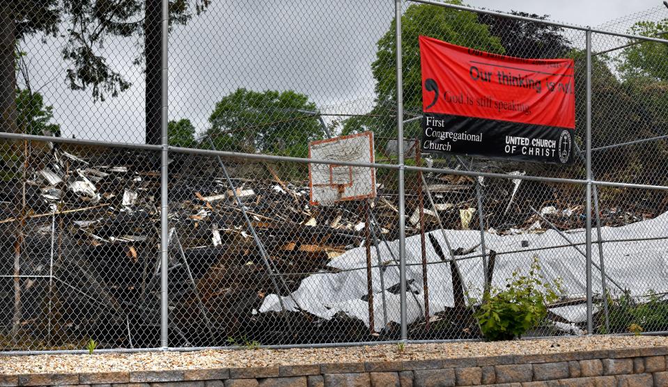 A banner hangs from the fence around the First Congregational Church's partially covered wreckage Monday.