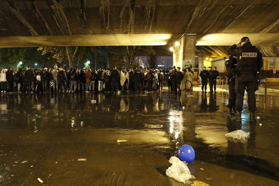 Police officers guard migrants as they clear an area Thursday, Nov. 7, 2019 in the north of Paris. Migrant encampments are becoming increasingly visible in the French capital. Police cleares Thursday several thousand people from a northern Paris neighborhood where migrants have repeatedly been removed. They are taken to shelters, and some eventually sent home. (AP Photo/Francois Mori)