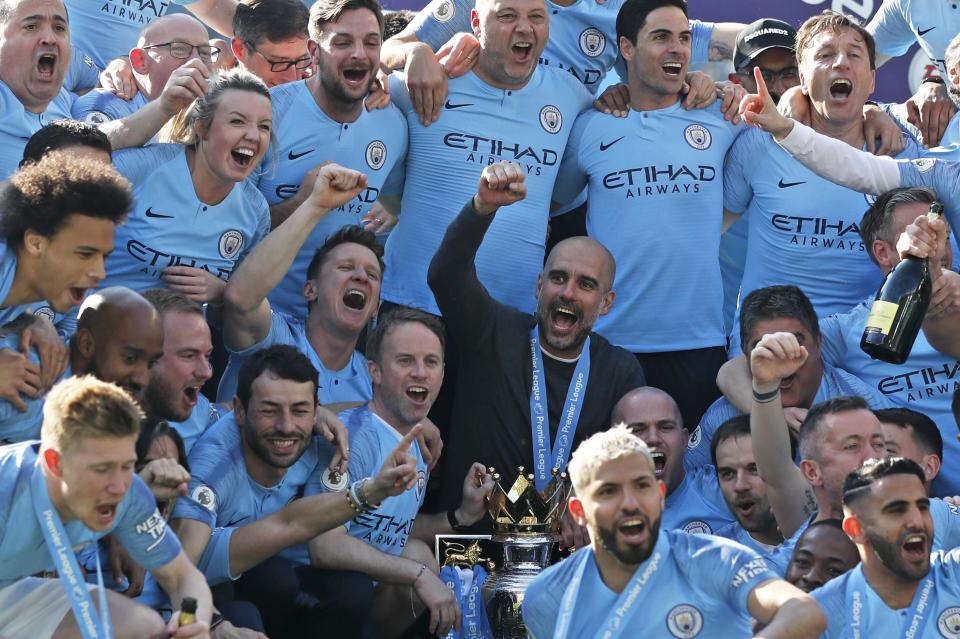 Manchester City coach Pep Guardiola, center, celebrates with players and staff after they won the English Premier League on the final day of the season. (AP)