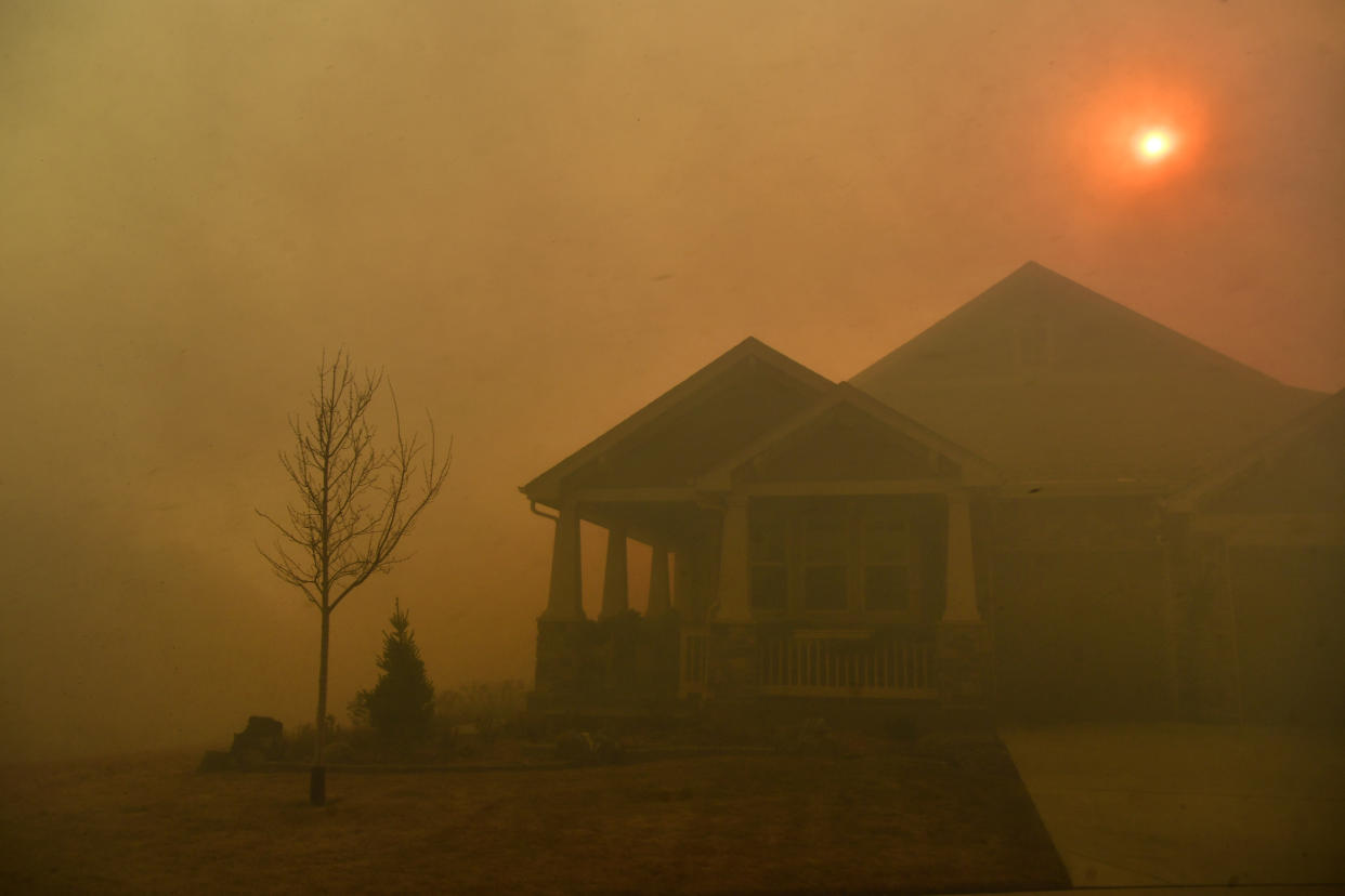 A home is surrounded by smoke and haze cause by a fire.