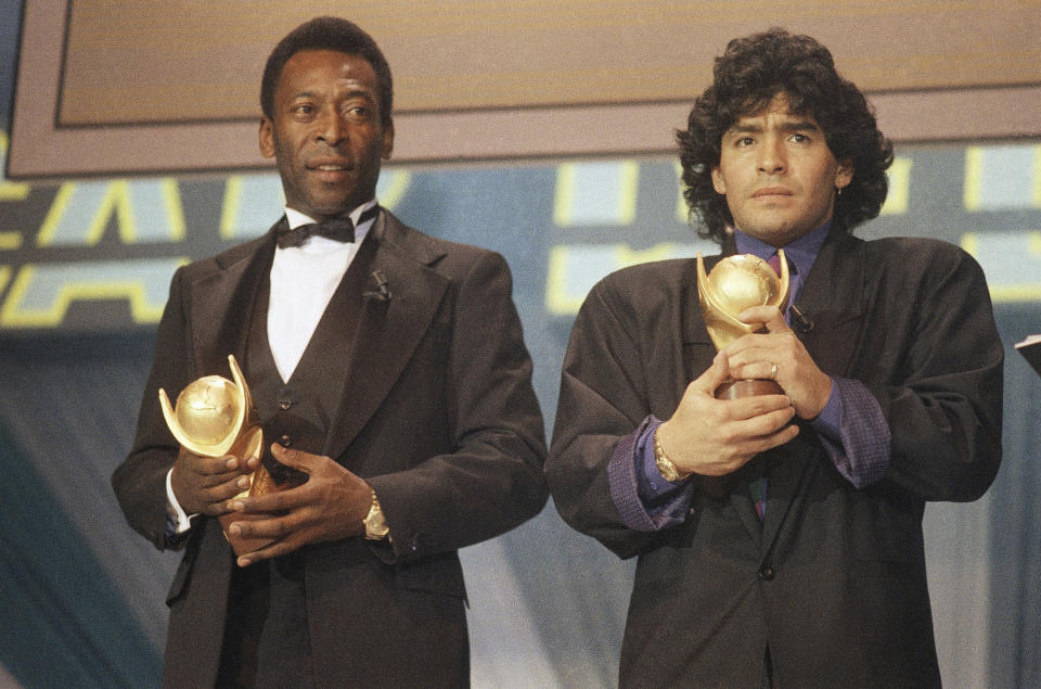 CORRECTS LOCATION - FILE - In this March 1987 file photo, Pele, left, and Diego Maradona, hold trophies during an awards ceremony in Italy. The Argentine soccer great who was among the best players ever and who led his country to the 1986 World Cup title before later struggling with cocaine use and obesity, died from a heart attack on Wednesday, Nov. 25, 2020, at his home in Buenos Aires. He was 60. (AP Photo/File)