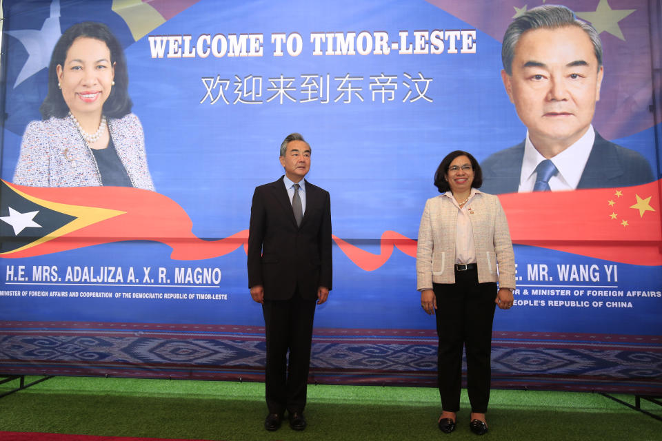 Chinese Foreign Minister Wang Yi, left, stands on the stage with his East Timorese counterpart Adaljiza Magno as they pose for photographers during their meeting in Dili, East Timor, Friday, June 3, 2022. (AP Photo/Lorenio Do Rosario Pereira)